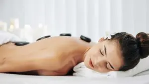 Frau liegt entspannt bei einer Hot & Cold Stone Massage auf der Liege